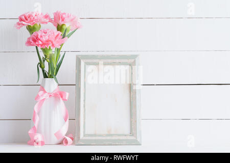 Valentines day and love concept. Pink carnation flower in vase with old vintage picture frame and red heart and on white background. Stock Photo