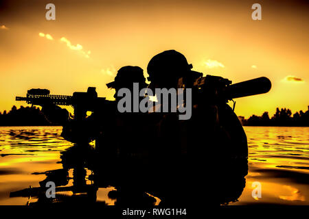 Silhouette of special forces soldiers during a river raid in the jungle. Stock Photo