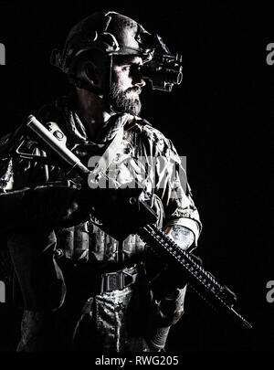 Studio contour backlight shot of special forces soldier in uniform with weapon. Stock Photo