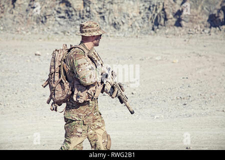 Soldier in field uniform with rifle in the desert. Stock Photo