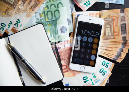 Smartphone with Calculator on Lot of Euro Banknotes Money and Opened Notebook Business Concept Stock Photo