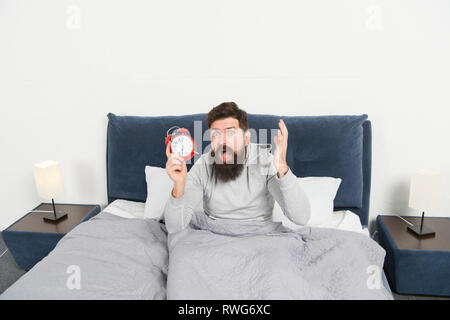 Tips for waking up early. Man bearded hipster sleepy face waking up. Daily schedule for healthy lifestyle. Again unhappy in morning. Alarm clock ringing. Problem early morning awakening. Get up early. Stock Photo