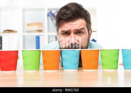 Choose from alternatives. Man bearded choosing one of lot colorful paper cups. Alternative concept. Pick one. Diversity and recycling. Eco paper cup. Coffee to go paper cup. How many cups per day. Stock Photo