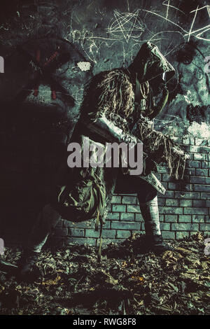 Post apocalypse survivor in gas mask and ghillie cape sneaking around in underground tunnel. Stock Photo