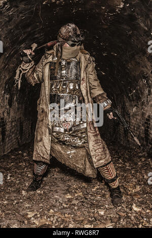 Post apocalyptic survivor holding a pistol and machete in an abandoned tunnel. Stock Photo