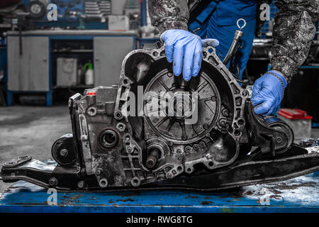 variabel hop aansluiten A close-up of a young man repairman in a working uniform of cars is  repairing an automatic gearbox of a used car in an auto repair shop. The  concept o Stock Photo - Alamy