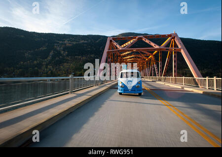 Driving a Vintage VW van across orange bridge in Nelson BC Stock Photo