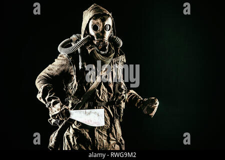 Post apocalyptic creature in ragged clothes and gas mask, armed with a handmade weapon Stock Photo