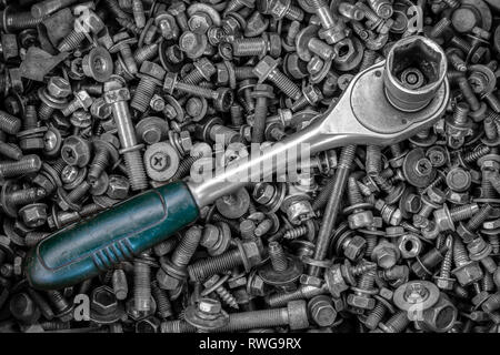 Flat Lay metal ratchet  lie on the background of various metal cogs, screws and nails, top view. Close-up Carpenter's Tool Kit Stock Photo