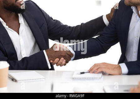 Closeup diverse businessmen in suits greeting each other with handshake Stock Photo