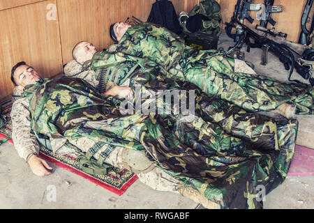 Tired U.S. Marines sleeping on the floor covered with poncho liners and sleeping bags. Stock Photo