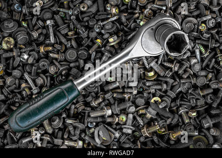 Flat Lay metal ratchet  lie on the background of various metal cogs, screws and nails, top view. Close-up Carpenter's Tool Kit Stock Photo