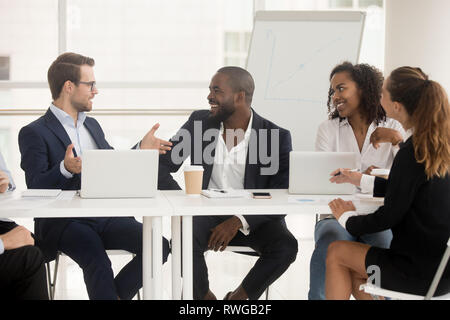 Multiracial employees sitting at boardroom desk listening team leader Stock Photo