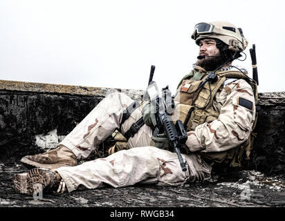 Soldiers sitting on rooftop observation post of an old ruined building. Stock Photo