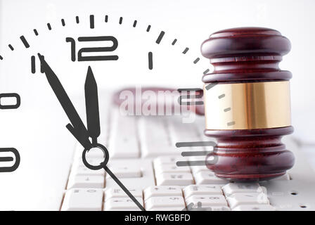 Judges or auctioneers wooden and brass gavel on a white computer keyboard and clock composite in a conceptual image Stock Photo