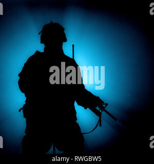 Silhouette of modern infantry soldier standing with assault rifle on colored background. Stock Photo