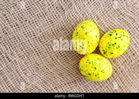 Easter colored eggs are yellow with green splashes. On linen brown fabric. Stock Photo