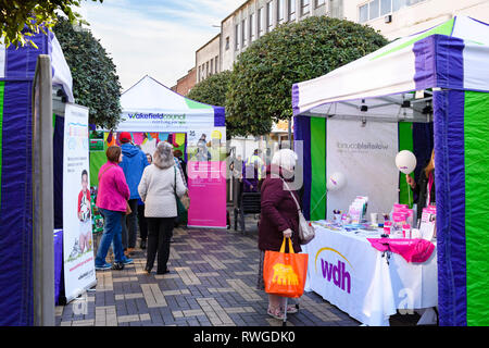 People shopping at busy Wakefield Food, Drink & Rhubarb Festival 2019, visiting colourful market trade tents or stalls - West Yorkshire, England, UK Stock Photo