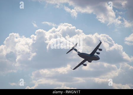 A Boeing C-17 Globemaster III in flight, banking against a cloudy sky Stock Photo