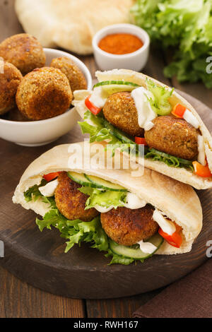 Falafel and fresh vegetables in pita bread on wooden board. Stock Photo