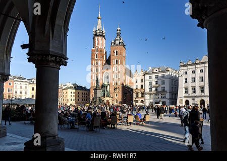 Krakow, Poland - February 16, 2019: Tourists are visiting the Main Square with famous historical architecture in Krakow in a sunny day. Stock Photo