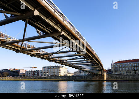 Krakow, Poland - February 16, 2019: People pass through the famous footbridge of Father Bernatka on the Vistula River in Krakow on a sunny day. Stock Photo