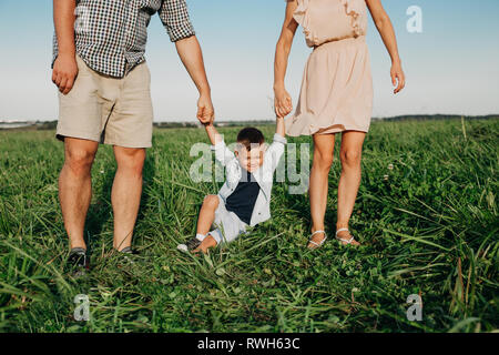 Parents hold baby's hands. Happy family in park in summer Stock Photo