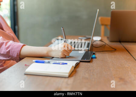 Graphic designer using digital tablet with laptop on the desk. Stock Photo