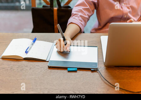 Graphic designer using digital tablet with laptop on the desk. Stock Photo