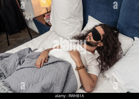 Nice bearded man wearing a special sleeping mask Stock Photo