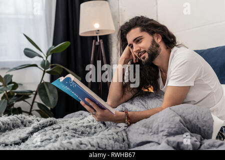 Positive nice young man focusing on reading Stock Photo