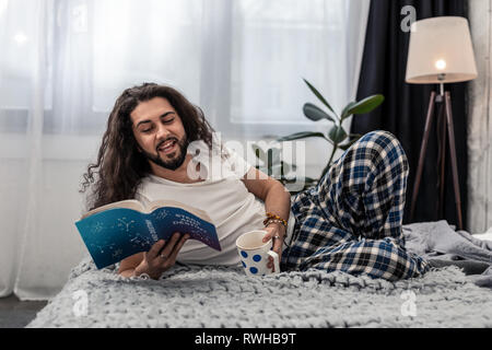 Joyful positive man lying with a coffee cup Stock Photo