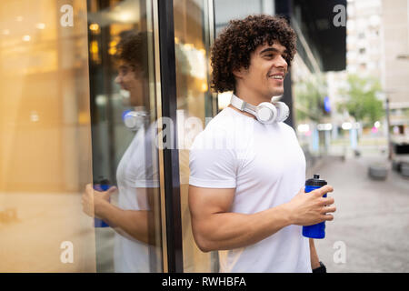 Handsome runner man drinking fresh water in urban area Stock Photo