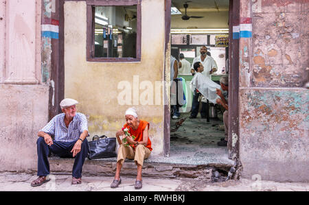 Havana, Cuba. 30th May, 2009. An elderly couple sit and relax on a step outside a barbers shop in Havana, Cuba. Stock Photo