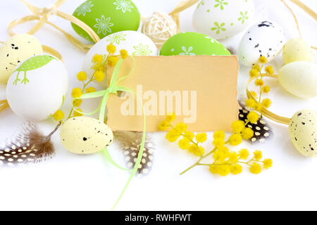 Easter eggs and mimosa flowers on white background with blank card to greet Stock Photo