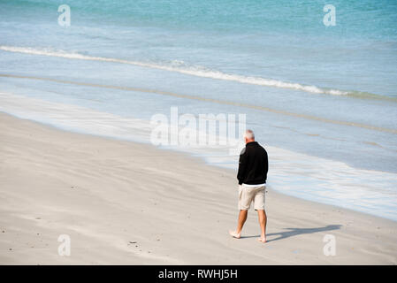 Australian senior man walking alone along beach deep in thought, Victoria Australia Stock Photo
