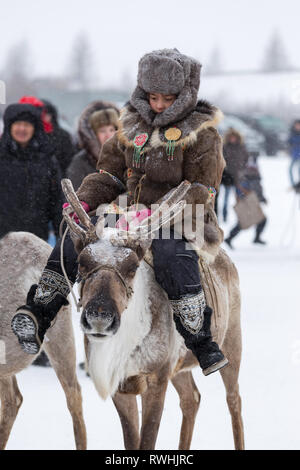 Iengra, Neryungri District, Yakutia, Russia. 5 March 2016. The Evenk girl in national clothes riding a reindeer during the celebration of the reindeer Stock Photo