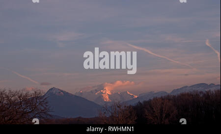 The highest mountain in Europe turns pink in the sunset as the clouds gather around the high snowy alpine peak.