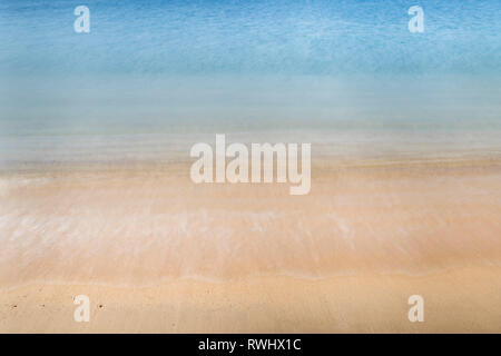 Abstract photo of motion blur of wave crashing on sand at a sandy beach Stock Photo
