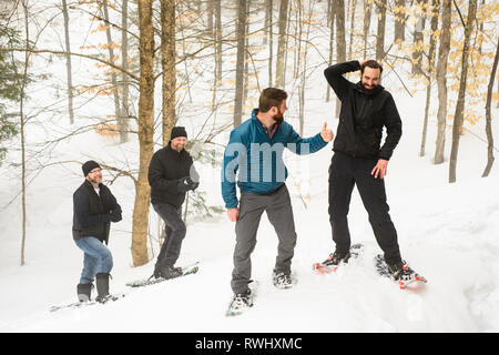 Group of friends (all late 30s) snowshoeing through the woods in winter. Mont Tremblant, Quebec, Canada Stock Photo