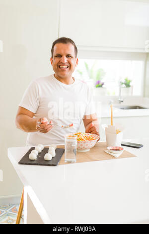 Middle age man eating asian food at home Stock Photo