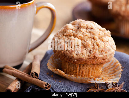 Closeup of a cinnamon muffin and sticks on a blue napkin with cup of coffee and muffins in background Stock Photo