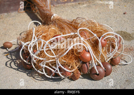 Old fishing net with cords and floats on the beach Stock Photo