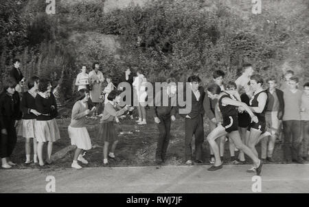 1960s, school sports, youths running in a relay race being encouraged by the watching girls and boys standing beside the track, England, UK. Stock Photo