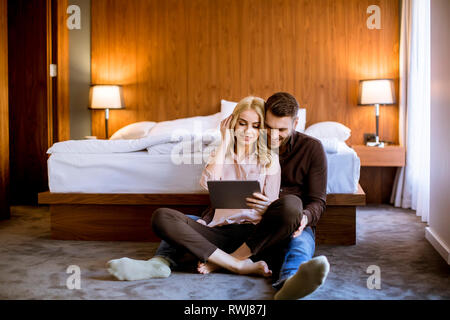 Romantic young happy couple in love sitting on floor resting and  having fun surfing internet Stock Photo
