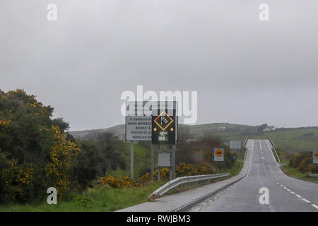 County Donegal, Ireland. 06 March 2019. Ireland weather - after heavy overnight rain, it was a day of strong winds and driving rain across County Donegal. High winds warning sign at the Harry Blaney Bridge as viewed from the inside of a car. Credit: David Hunter/Alamy Live News. Stock Photo