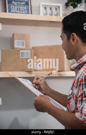 asian worker look at the boxes on a wooden shelf in the office room and checking Stock Photo