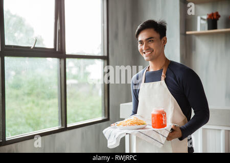 handsome asian waiters wearing apron serving meal and beverage with smile Stock Photo