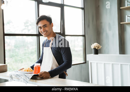 asian male waitress with food looking at camera and smiling Stock Photo