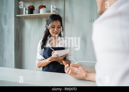 asian female waitress taking a note on customer order Stock Photo